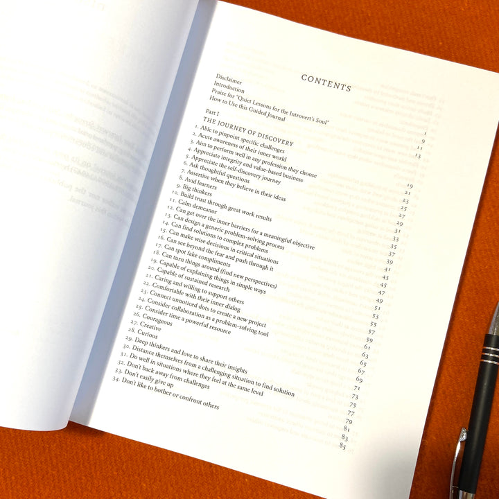 Awaken_Your_Introvert_Strengths_Self-Coaching_Journal Contents book with a pen on an orange surface