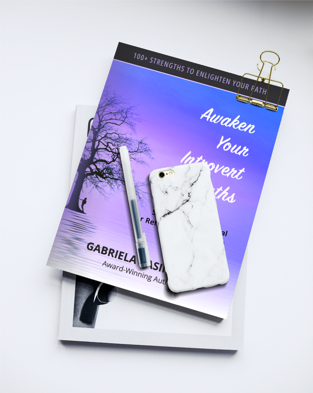 Book titled 'Awaken Your Introverts Strengths by Gabriela Casineanu with a pen and phone on a white background