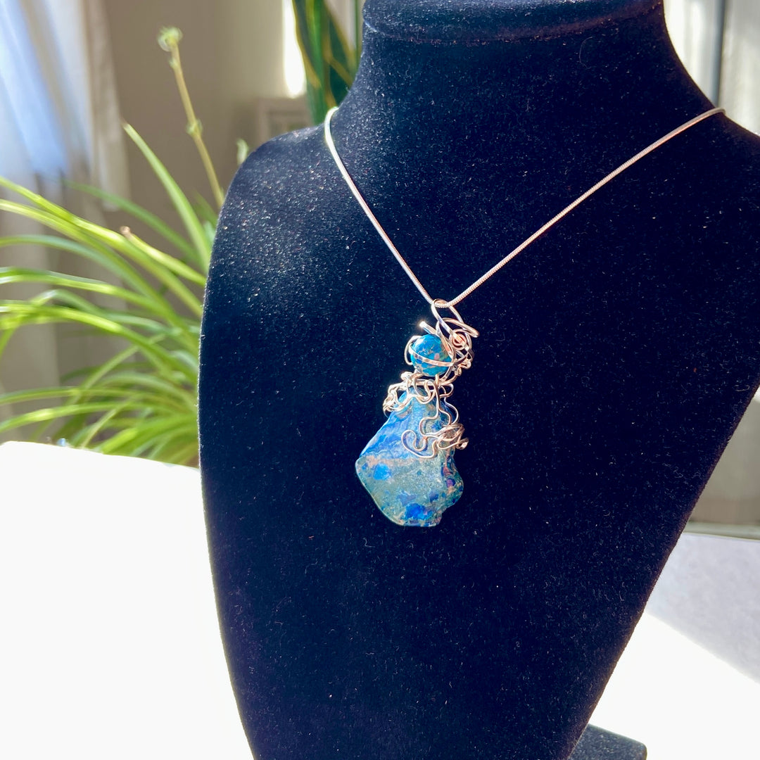 Blue Jasper stone stone pendant in a silver wire wrap on a black display