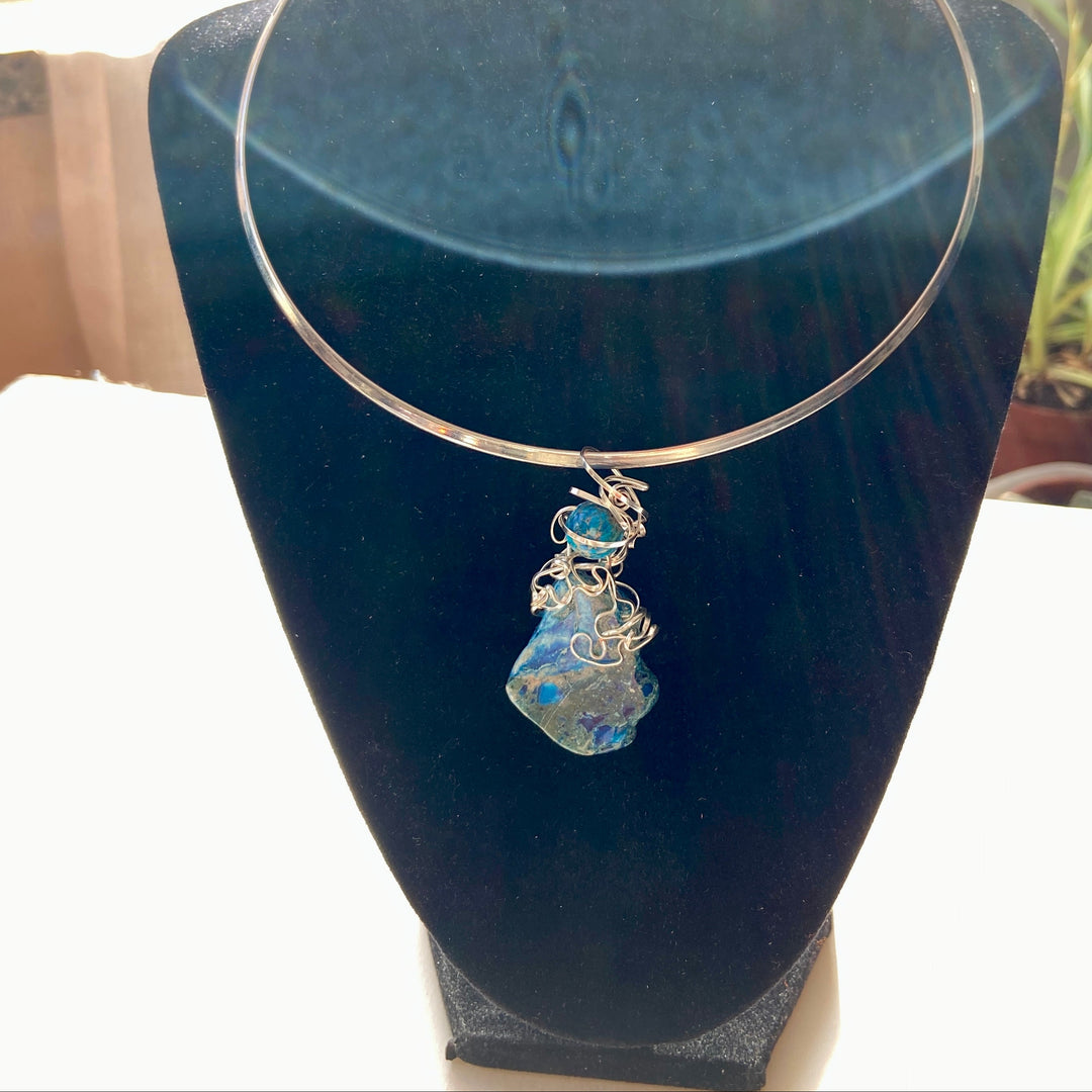 Blue Jasper stone stone pendant in a silver wire wrap on a black display