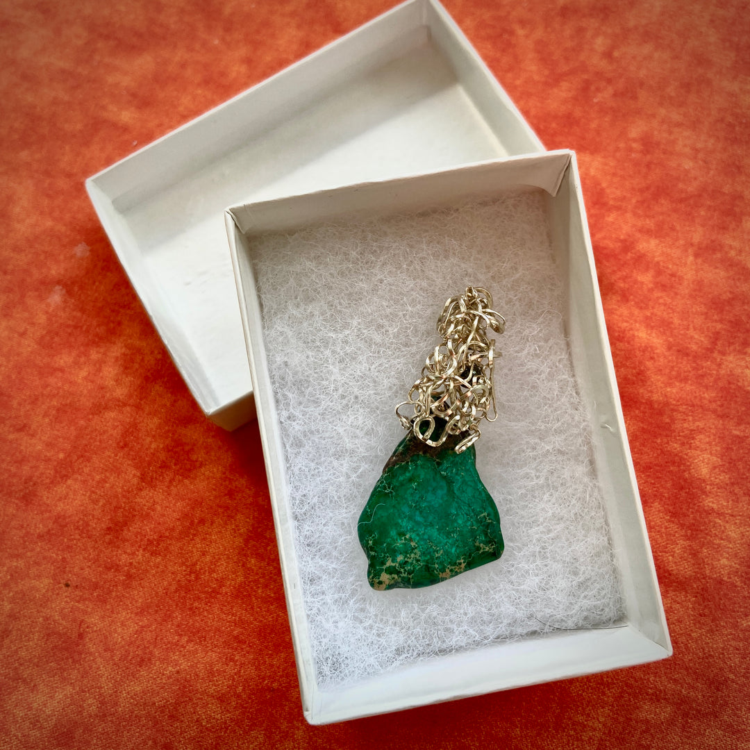 Green Jasper stone pendant in a white box on a orange background