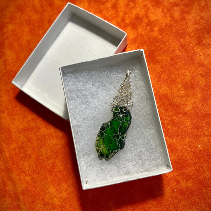 Green Jasper stone pendant inside a white box on an orange surface