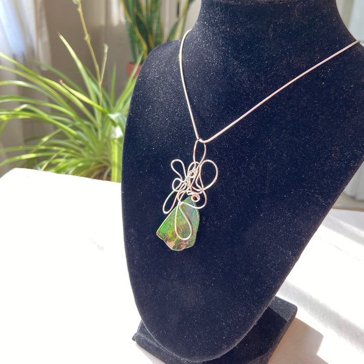Green Jasper stone pendant with silver wire wrapping on a black display