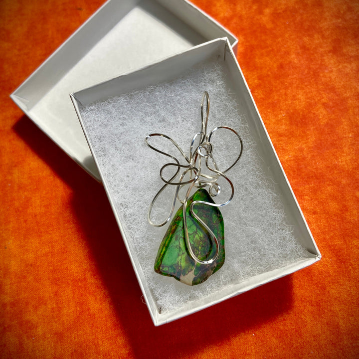Green Jasper stone pendant with silver wire wrapping in a white box on an orange background