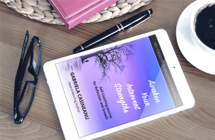 Tablet displaying a Awaken Your Introvert Strengths Journal ebook cover with glasses, pen, and coffee cup on a wooden surface