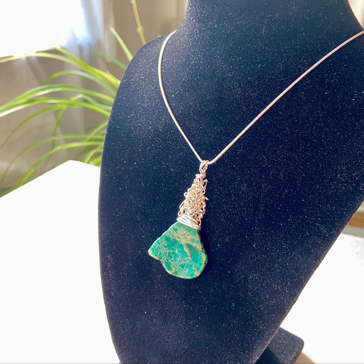 green Jasper gemstone and silver wire wrap pendant on a black diaplay
