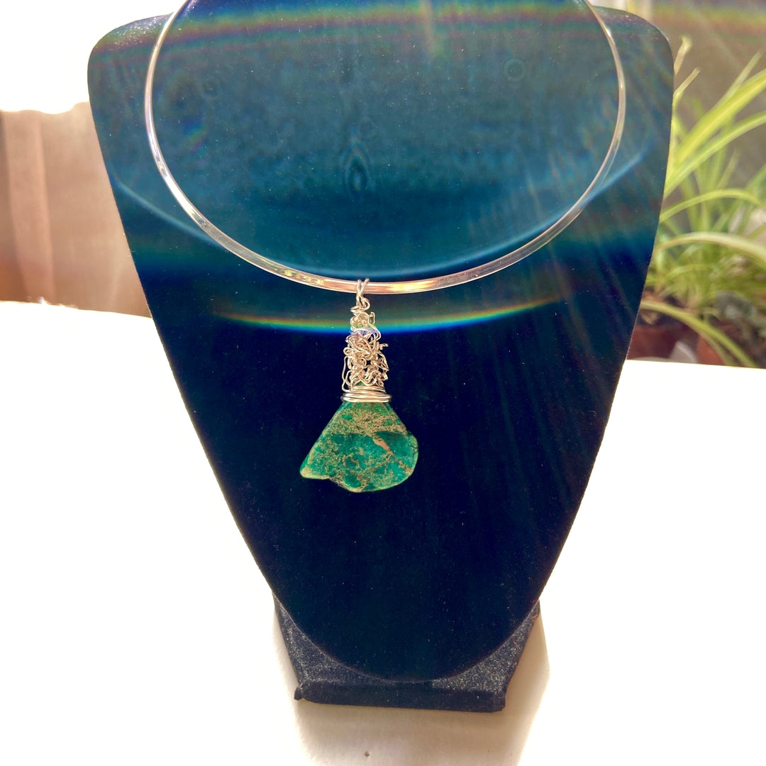 Necklace with a green Jasper gemstone and silver wire wrap pendant on a black stand