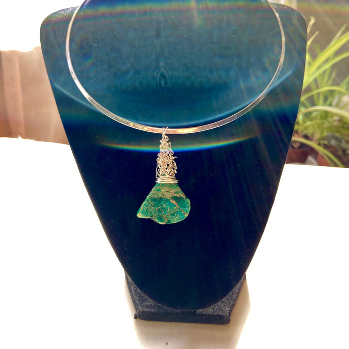 Necklace with a green Jasper gemstone and silver wire wrap pendant on a black stand