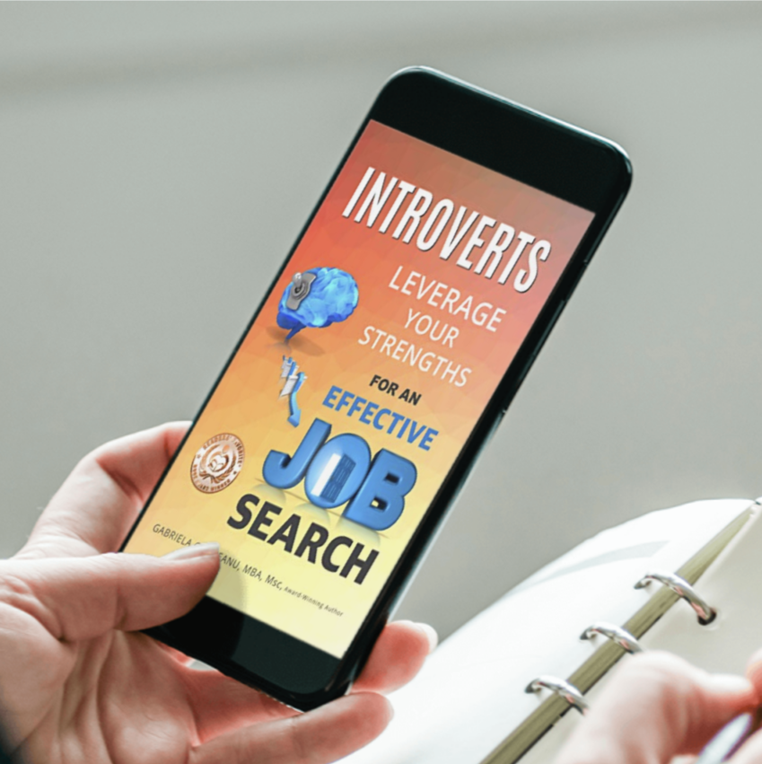 mobile phone showing the cover of ebook Introverts Leverage Your Strengths for an Effective Job Search -  in one hand, notebook, and pen in the other