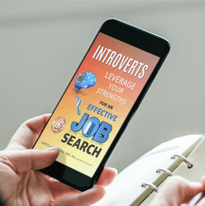 mobile phone showing the cover of ebook Introverts Leverage Your Strengths for an Effective Job Search -  in one hand, notebook, and pen in the other