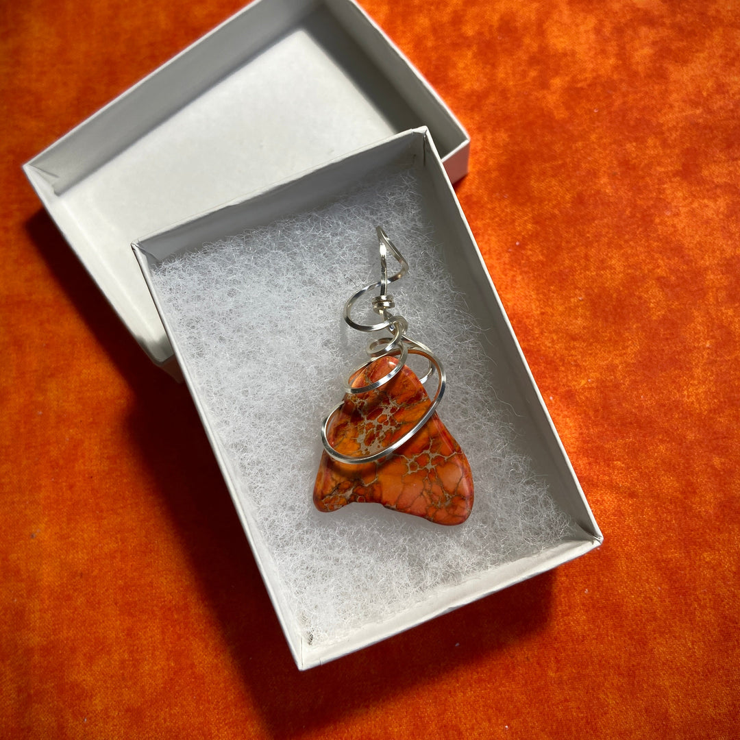 Jewelry box with an orange Jasper stone pendant and silver-plated spiral on an orange background