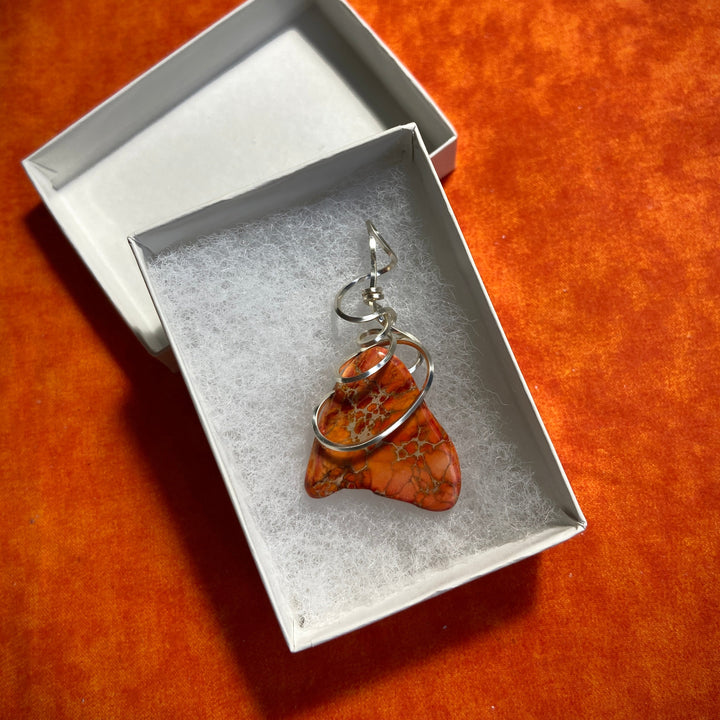 Jewelry box with an orange Jasper stone pendant and silver-plated spiral on an orange background
