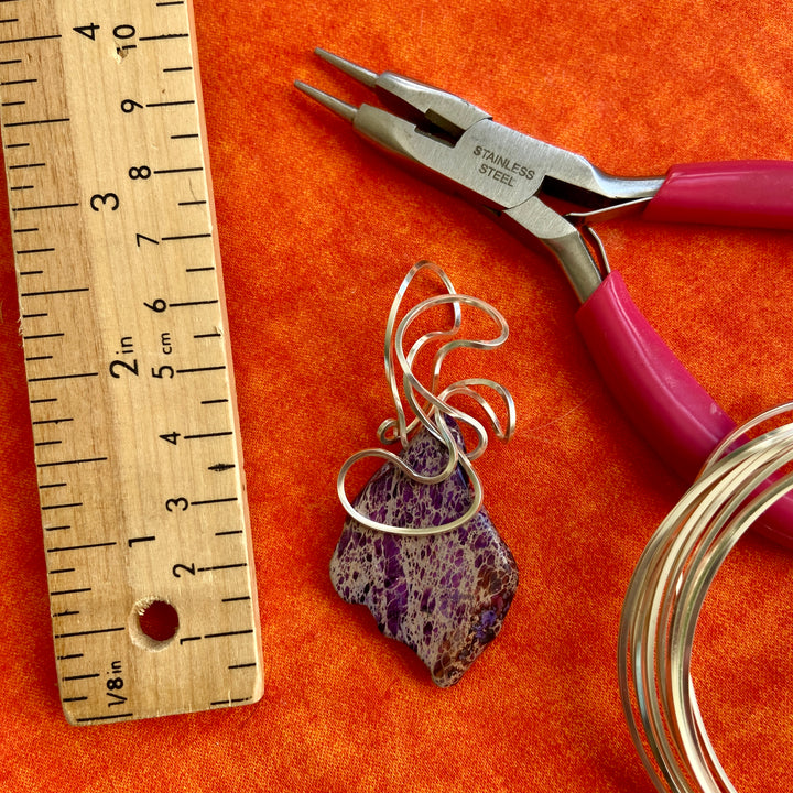 Jewelry-making tool set with pliers, wire, and a purple stone pendant on an orange background.